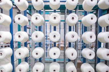 Tekstil değirmenindeki büküm makinesinin üzerindeki bir grup bobbin ipliği. Tekstil fabrikasında iplik topu yapmak. Tekstil endüstrisi - Tekstil fabrikasında dönen makinenin iplik makaraları