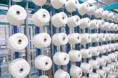 Tekstil değirmenindeki büküm makinesinin üzerindeki bir grup bobbin ipliği. Tekstil fabrikasında iplik topu yapmak. Tekstil endüstrisi - Tekstil fabrikasında dönen makinenin iplik makaraları