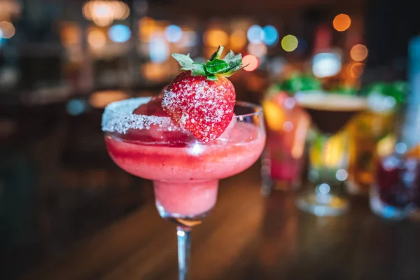 ピンクバーでイチゴと新鮮なカラフルなエキゾチックなアルコール冷凍カクテル カラフルなピンクのソフトドリンクとストロベリーのバーデスク — ストック写真