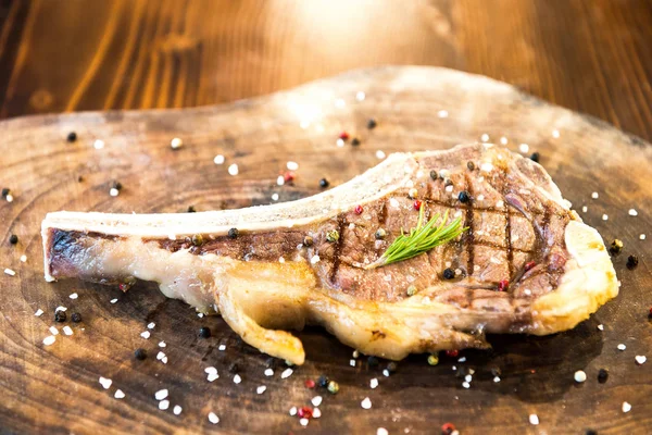 Grilled tasty delicious lamb chop on wooden board on rustic wood table with herb. Steak house restaurant concept image.