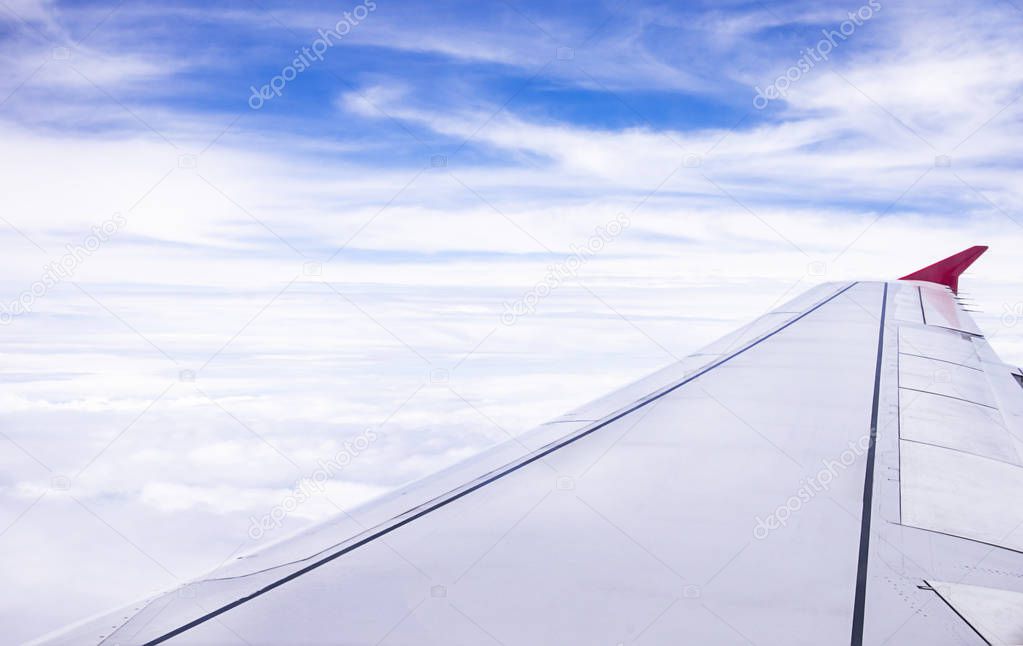 Wing of an airplane flying above Blue sky background with white clouds