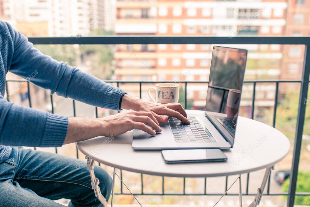 Unrecognizable Caucasian middle-aged man working from home on his laptop due to confinement by the coronavirus, covid-19.