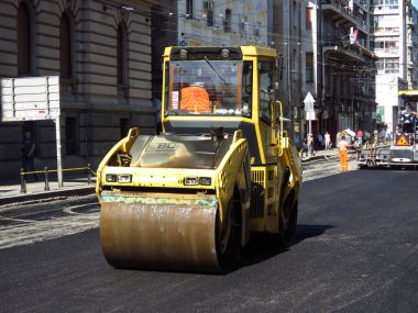 Belgrad, Sırbistan, 1 Ekim 2019. Steamroller and Paver şehir merkezinde asfalt caddeyi bitiriyor..