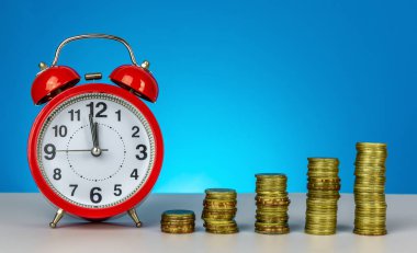 Gelecek için para biriktiriyorum. Zaman kavramı kaydetmek için kaydetme. Saat ve sikke üzerinde mavi arka plan istifleme.