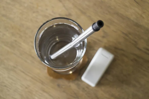 Reusable metal drinking straw in glass of water — Stock Photo, Image
