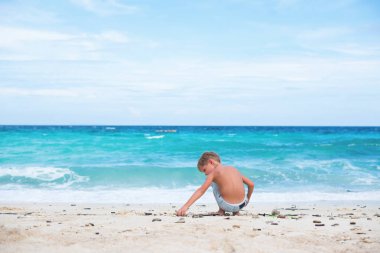 doğal sopalarla oynayan çocuk. mavi deniz beyaz kum. tropikal seyahat rüyalar kavramı. Çocuk doğaya bağlı. kopya alanı
