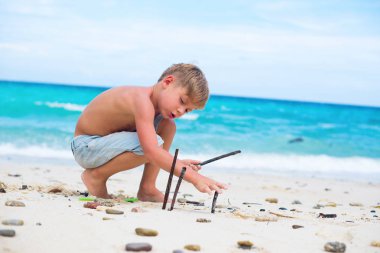 doğal sopalarla oynayan çocuk. mavi deniz beyaz kum. tropikal seyahat rüyalar kavramı. Çocuk doğaya bağlı. kopya alanı