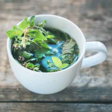 ahşap arka plan tonda sağlıklı bevarage görüntü üzerinde beyaz Kupası'nda bitkisel yeşil nane çayı