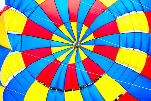 Falling open multicolor parachute in air Bright background Tense slings Summer entertainment on beach Rainbow Parachute on the beach. Para sailing adrenaline