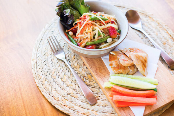 Thai food Som Tam Spicy Papaya salad with chicken served with vegetables carrot cucumbers on wooden tray Asian cuisine national traditional dish