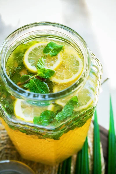 Open lid jar lemonade fresh lemon sliced leaves mint Ice cold useful juicy beverage in hot weather Refreshing drink Summer time