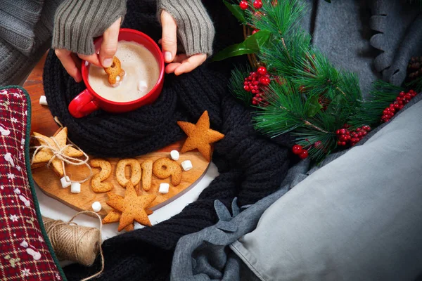 Female hand holds 8 from expiring year to celebrate 2019 fresh hot cup beverage coffee with gingerbread cookies Dark background Top view Flat lay Winter cozy theme