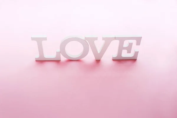 Słowo miłość biały wielkość liter na różowym tle — Zdjęcie stockowe