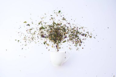 Kupası ve kuru yaprakları bitkisel çay beyaz üzerinde dağınık