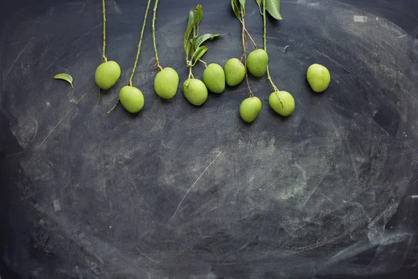 Ganz kleine wilde grüne Mangos auf dunklem Hintergrund — Stockfoto