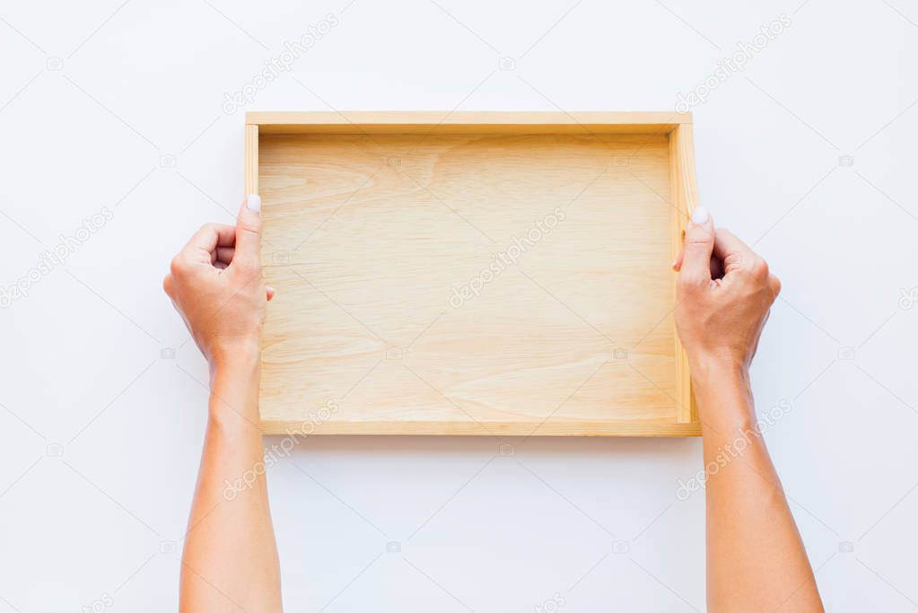 Female hands holding wooden empty tray. Woman