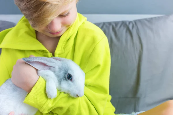 Niño feliz en chaqueta amarilla jugando conejo — Foto de Stock