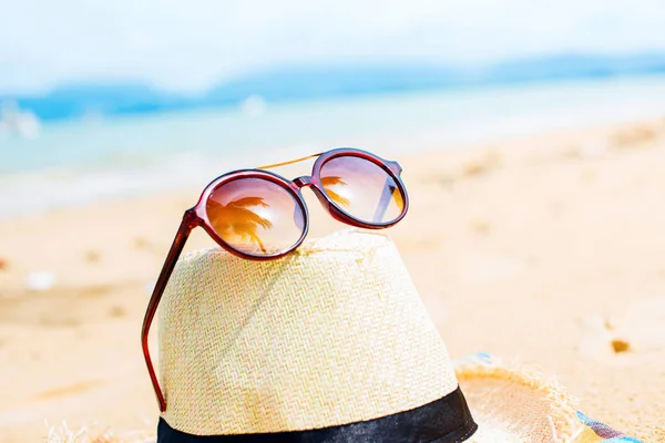Sunglasses with reflection palms straw hat beach — Stock Photo, Image