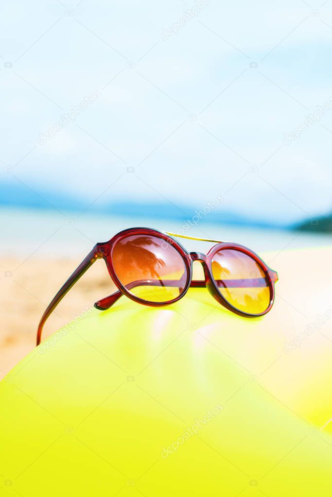 Sunglasses reflection palms on yellow floating ring