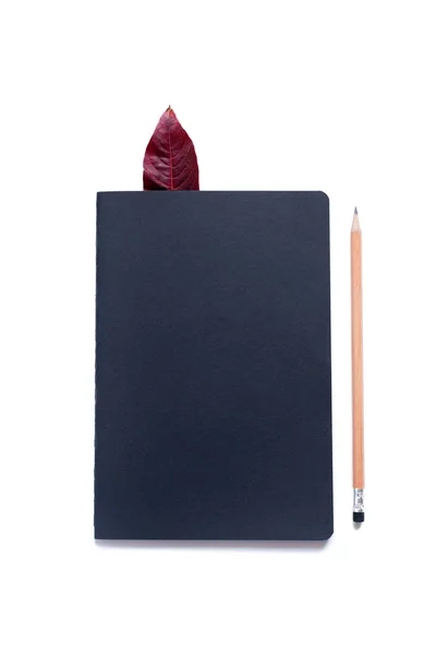 Закрытая черная тетрадь карандаш один красный осенний лист — стоковое фото
