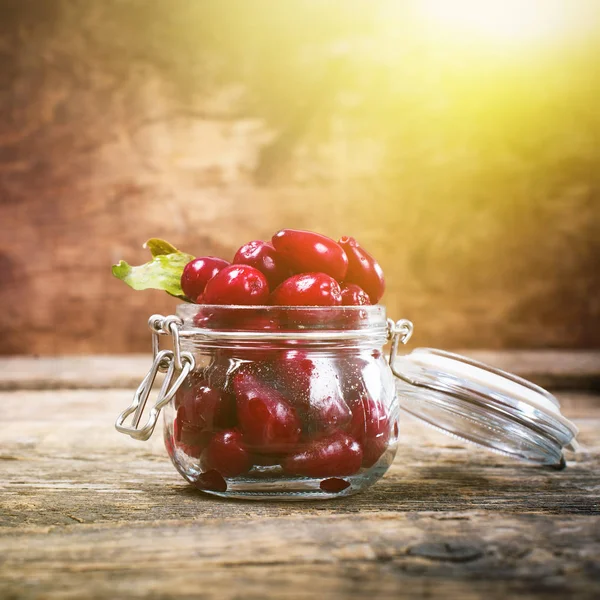 Ripe red cornel berries in small glass jar — Stock Photo, Image