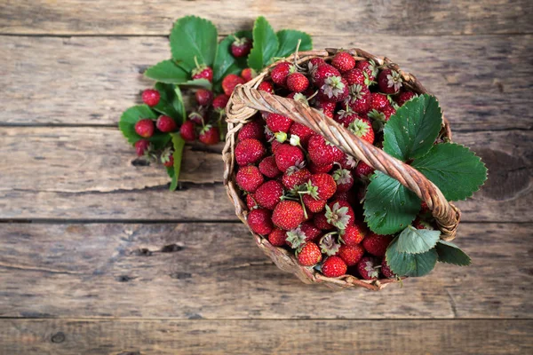 Erdbeere im Korb mit grünen Blättern auf Holz — Stockfoto