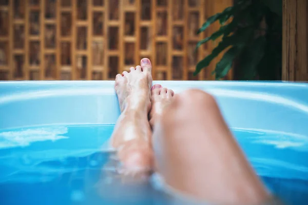 Woman with raised legs in the bathtub. Healthcare and SPA procedure. Bath treatment. Wellbeing, relaxation concept. Open air resort hotel