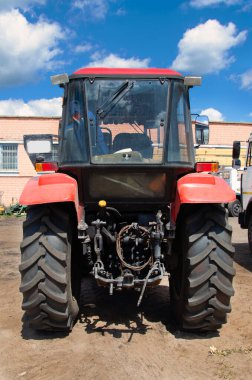 Arka taraftaki büyük traktör lastikli kırmızı traktör. Almanya 'da güneşli bir günde yepyeni bir traktör lastiğinin yakın plan çekimi..