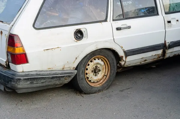 ゴミ収集車のアスファルトの上に放置された古い車が立っています — ストック写真