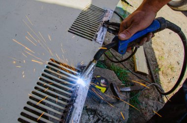 Kaynakçı, zanaatkar, eski bir arabanın parçalarını sindiriyor.