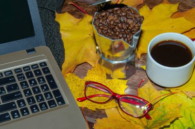 Kırmızı bardakta sıcak kahve, buharlı ve gözlüklü dizüstü bilgisayarlı, ahşap arka planda, kahve molası konsepti.