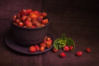 Düşük anahtar sahnede kahverengi kumaş üzerine bir kase taze çilek