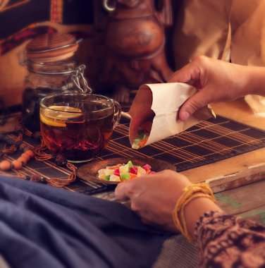 Çay ve tatlılar. Kadın şeker bir tabağına koyuyor. Doğu tarzı.