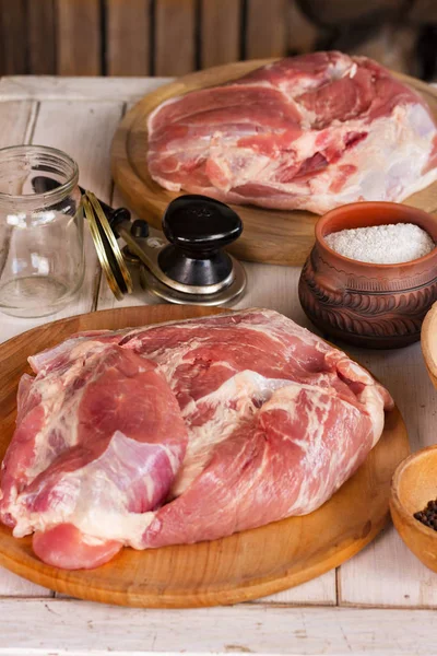 Meat stew, photo recipe. Three pieces of meat on wooden boards, salt, pepper, jars and lids