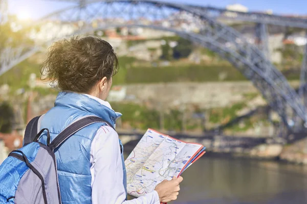 Parte posterior de la mujer viajera buscando la dirección correcta en el mapa —  Fotos de Stock