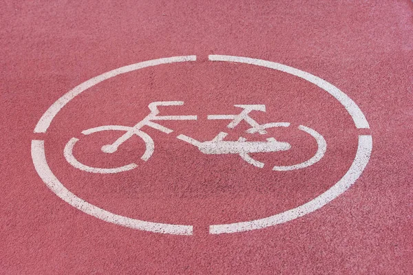 White bicycle sign on red bike path.