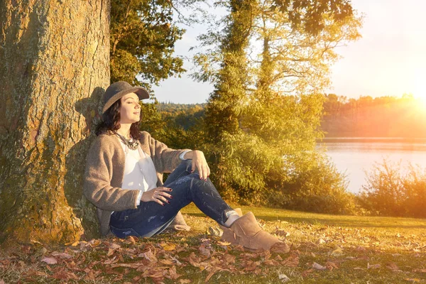 Жінка сидить спираючись на дерево в осінньому парку — стокове фото