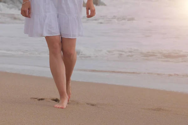 Femme en robe blanche marchant sur la plage de sable — Photo