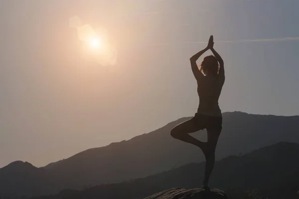 Mujer practicando yoga, montaña y fondo del cielo — Foto de Stock