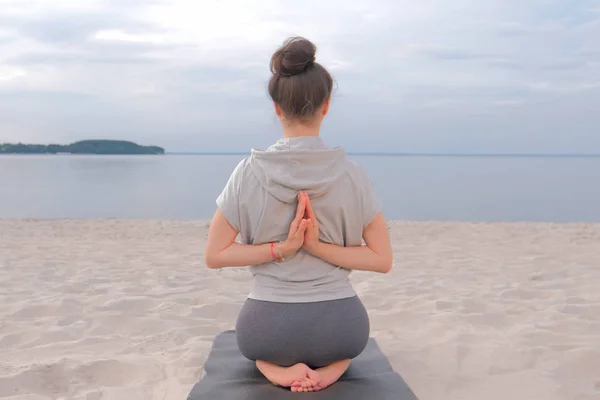 Mujer sentada en la esterilla de yoga y haciendo ejercicio de estiramiento de yoga — Foto de Stock