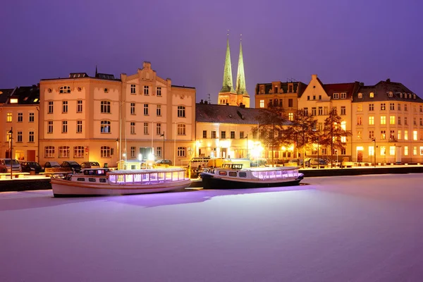 Boats on Frozen Trave river at nights. Lights on Lubeck city emb — Stock Photo, Image