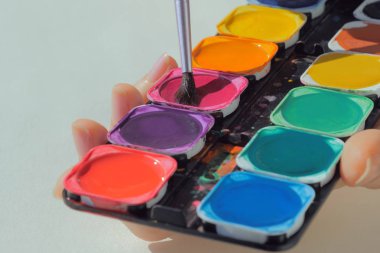 Sanat paletle boyalar ve boya fırçası tutan eller