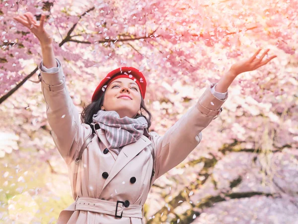 Mujer lanzando pétalos de flores disfrutando de jardín primavera — Foto de Stock