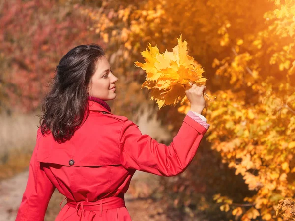 Mujer joven con hojas amarillas en el parque de otoño — Foto de Stock