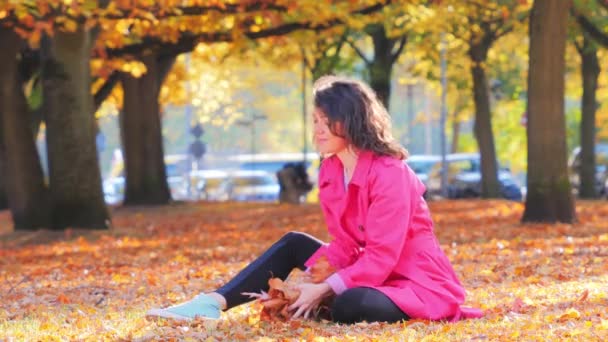 Gelukkig vrouw spelen met herfst bladeren in park — Stockvideo