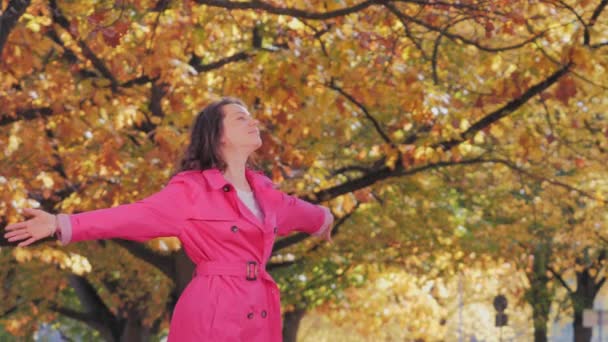 Šťastná krásná žena v podzimním parku se zvednutými pažemi — Stock video
