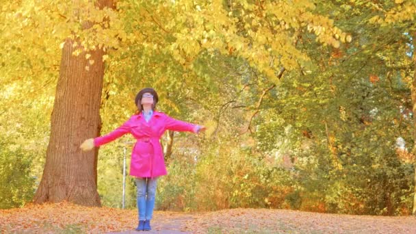 Mujer feliz con hojas de otoño en el parque — Vídeos de Stock