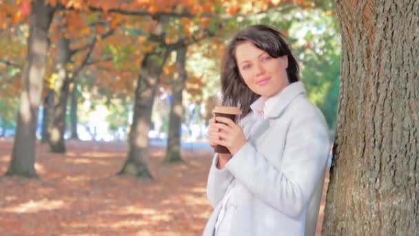 Νεαρή όμορφη γυναίκα πίνοντας καφέ και περπατώντας σε εξωτερικούς χώρους το φθινόπωρο — Αρχείο Βίντεο