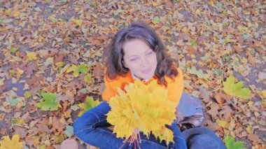 Sonbahar yapraklarıyla gülümseyen romantik kadın.