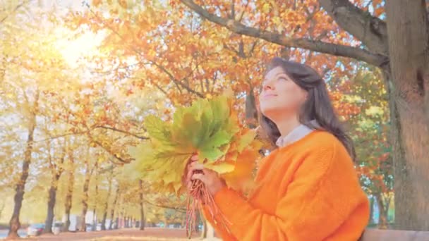 Feliz mujer romántica sonriente con hojas de otoño en el parque de otoño — Vídeos de Stock